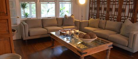 A living room with a glass coffee table, two sofas, and a wooden floor.