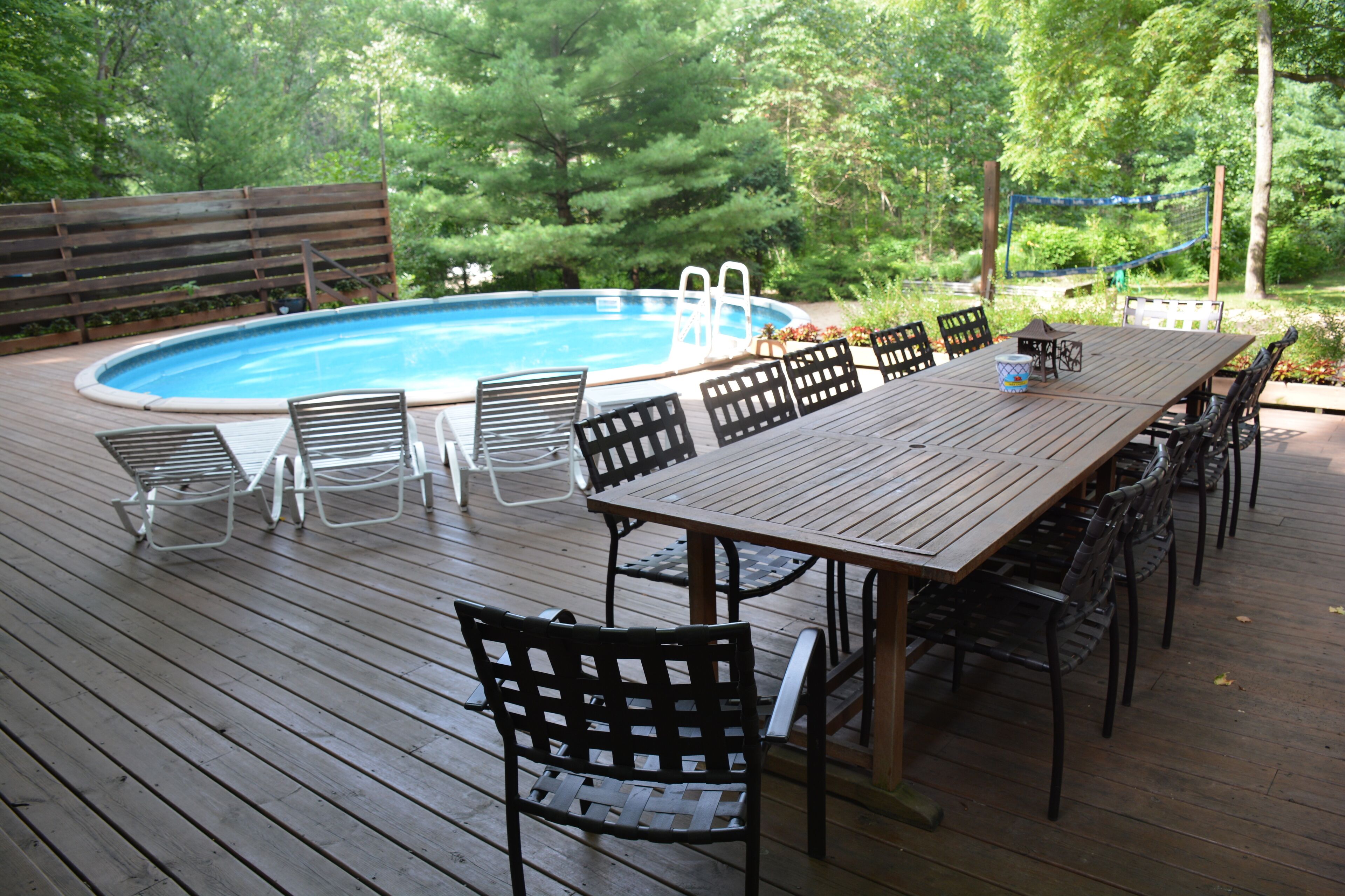 A wooden deck with a pool, surrounded by chairs and a table.