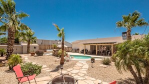 Un pati amb piscina, una zona de foc i mobiliari per a l'exterior.