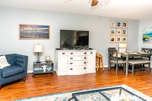 A living room with a television, a sofa, a dining table with chairs, and a coffee table.