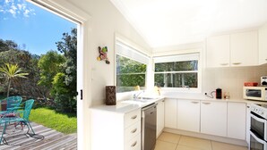 Una cucina moderna con mobili bianchi, elettrodomestici in acciaio inossidabile e un'ampia finestra con vista sul giardino.