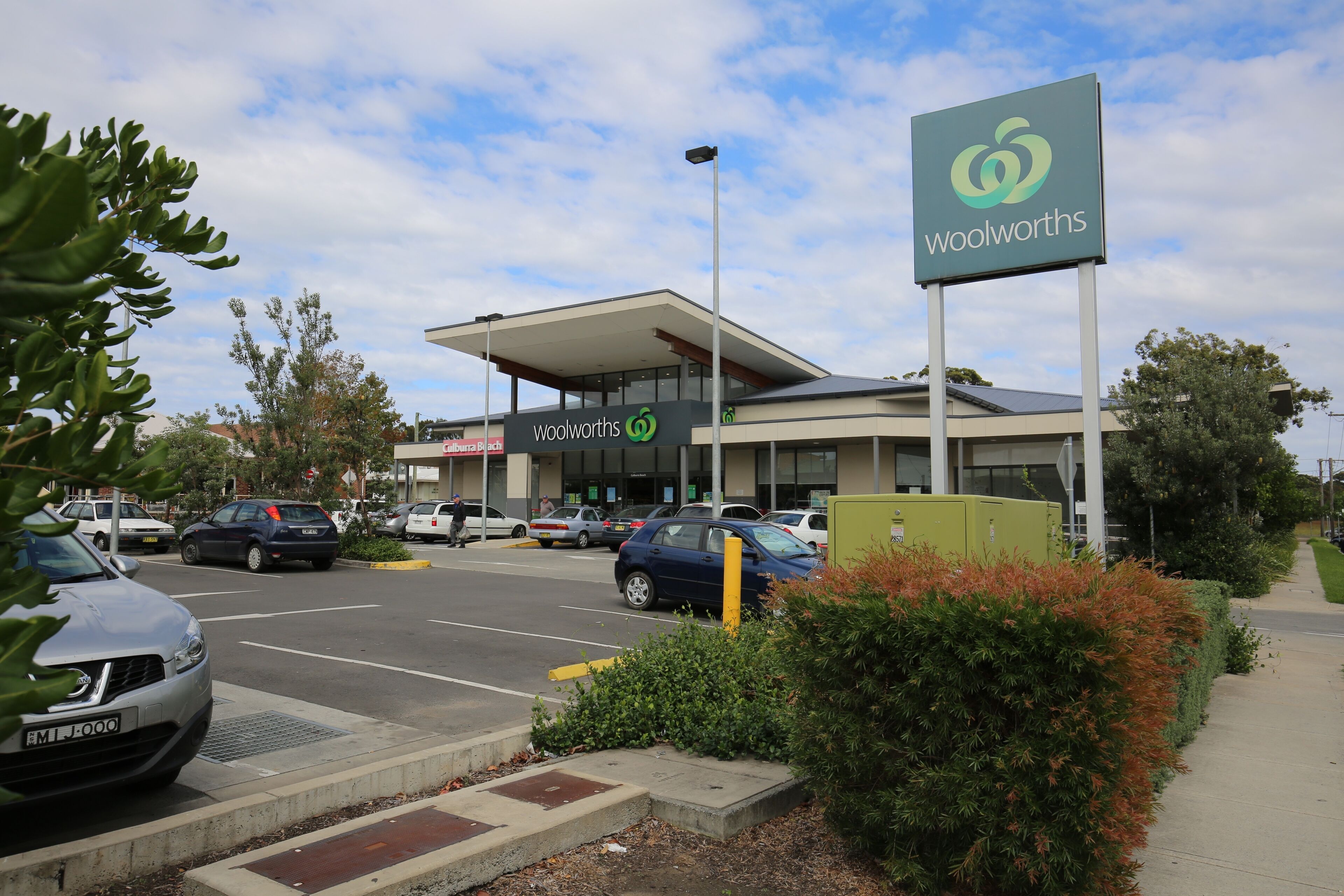 Uma loja Woolworths com design moderno, um estacionamento e céu claro.