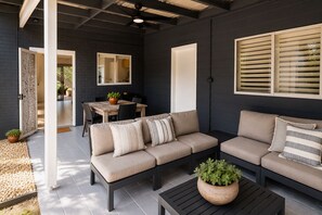A modern outdoor living area with a sofa, a dining table, and a coffee table.