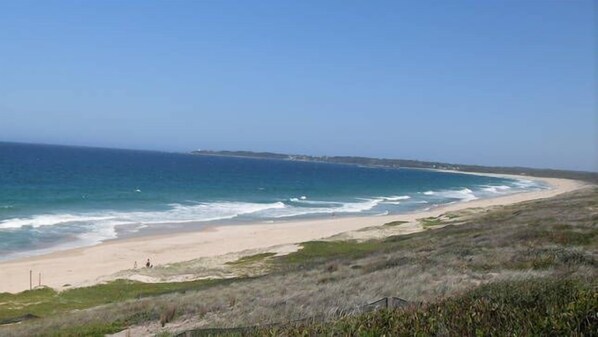 A beach with a clear view of the ocean and a distant shoreline.