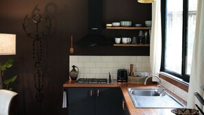 Een kleine keuken met een gasfornuis, een spoelbak en een raam.