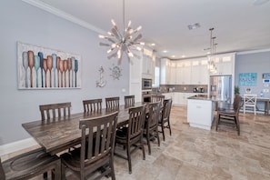 A spacious kitchen with white cabinets, a central island, and a dining area with wooden chairs.