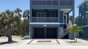 Un edificio di due piani con un balcone al secondo piano, un garage al piano terra e un cielo sereno.