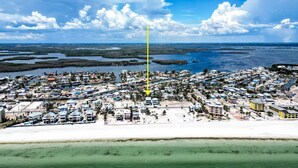 Vista aerea di una località costiera con un fitto complesso di edifici, una struttura verticale gialla ben visibile e una zona spiaggia.