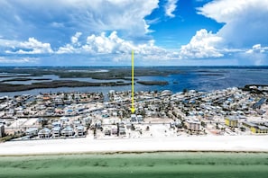 Une vue aérienne d’une ville côtière, avec un ensemble dense de bâtiments, une structure verticale jaune bien visible et une zone de plage.