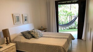 Un dormitorio con cama, mesita de noche, cómoda y vistas a una hamaca en el exterior.