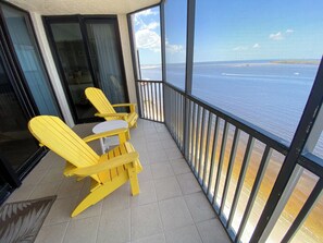 Un balcon avec des fauteuils Adirondack jaunes et une vue sur l’océan.