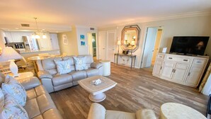 A spacious living room with a sofa set, a coffee table, and a television. - Sanibel Harbour Resort: Bay View Tower 1035 Relaxation awaits you at this beachfront retreat (Fort Myers)