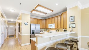 A kitchen with wooden cabinets, a white countertop, and a built-in microwave. - Pavilion Watch 2B - Oceanview Condo - Pool - Central Location - Elevator (Folly Beach)