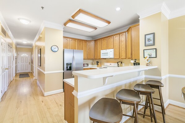 Una cocina con armarios de madera, encimera blanca y microondas empotrado.