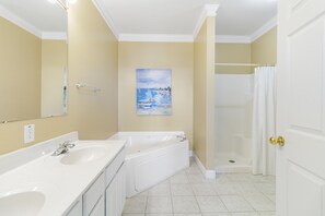 Un baño con dos lavamanos, una bañera, una ducha y un cuadro en la pared.