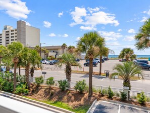 A parking lot with several cars, palm trees, and a building with a sign that reads 'TIDES'. - 2B Pavilion Watch | 3BR Condo with Ocean Views, Pool & Elevator | Walk to Beach & Dining (Folly Beach)