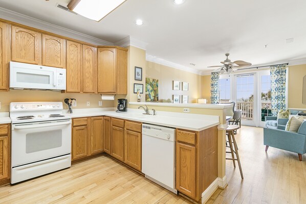 A kitchen with wooden cabinets, a white microwave, and a dishwasher.