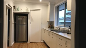 Una cocina compacta con un refrigerador de acero inoxidable, una ventana con vistas y un lavamanos con hervidor.