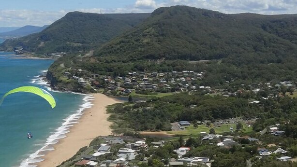 A coastal town with a beach, houses, and mountains in the background. - Jacaranda House where beach meets rainforest (Stanwell Park)