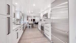 A modern kitchen with white cabinetry, stainless steel appliances, and a central island.