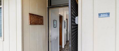 Un pasillo con un letrero de madera, una puerta y una placa numérica.