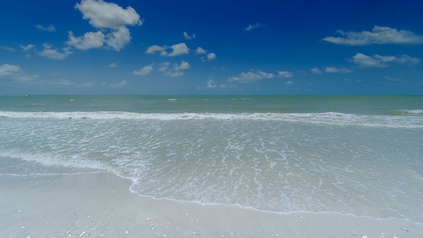 Een strand met heldere lucht en rustige golven.
