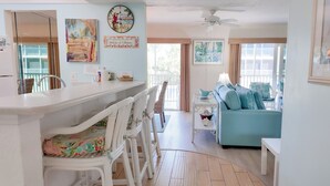 A beach-themed living room with a sofa, chairs, and artwork.