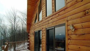 A wooden cabin with a balcony, large sliding glass doors, and a wooden railing. - Mountain retreat near Hunter/Windham Mountain (Prattsville)