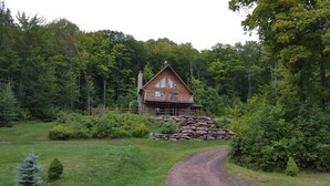 A cabin with a stone foundation, a balcony, and surrounded by dense forest. - Mountain retreat near Hunter/Windham Mountain (Prattsville)