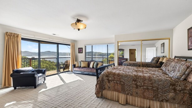 Een ruime slaapkamer met een groot bed, een bank, een stoel en een balkon met uitzicht op de heuvels.