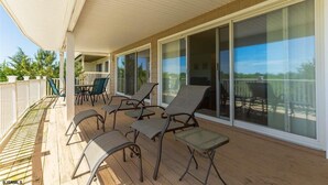 A covered outdoor area with sliding glass doors, a wooden deck, and several lounge chairs. - BEACHFRONT LARGE SOUTHEND 3 BEDROOM 2 BATH CONDO (Brigantine)