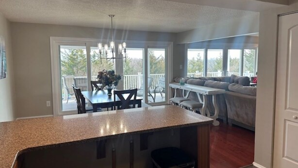 A spacious kitchen with a granite countertop, a dining area with a table and chairs, and a seating area with a sofa and a coffee table. - BEACHFRONT LARGE SOUTHEND 3 BEDROOM 2 BATH CONDO (Brigantine)