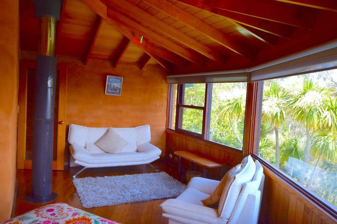 A cozy room with a white sofa, a bench, and a large window offering a view of greenery.