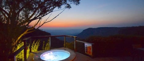 A hot tub with a view of a sunset and mountains.