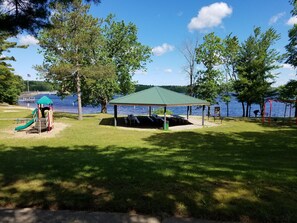 Un parc doté d’une aire de jeux, de tables de pique-nique et d’un kiosque situé au bord d’un lac.