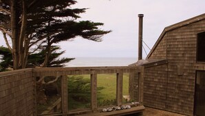 A wooden deck with a view of the ocean and a grassy area. - OCEAN FRONT-WHITE WATER VU from every room - above Del Mar Cove (The Sea Ranch)