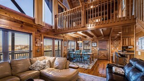 A spacious log cabin interior with a large living area, a dining area, and a kitchen.