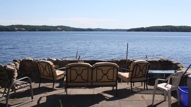 Un espace aménagé au bord du lac, avec des murs en pierre et des chaises disposées face à l’eau.