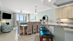 Un salon moderne avec un coin repas, une cuisine dotée de plans de travail en granit et une grande fenêtre offrant une vue dégagée.
