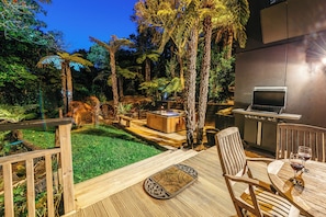 Una terraza con mesa y sillas de madera, un jacuzzi y una parrilla.