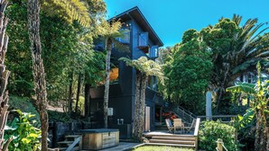 Ein modernes, zweistöckiges Haus mit Balkon, umgeben von üppiger Vegetation und einem gepflegten Garten.