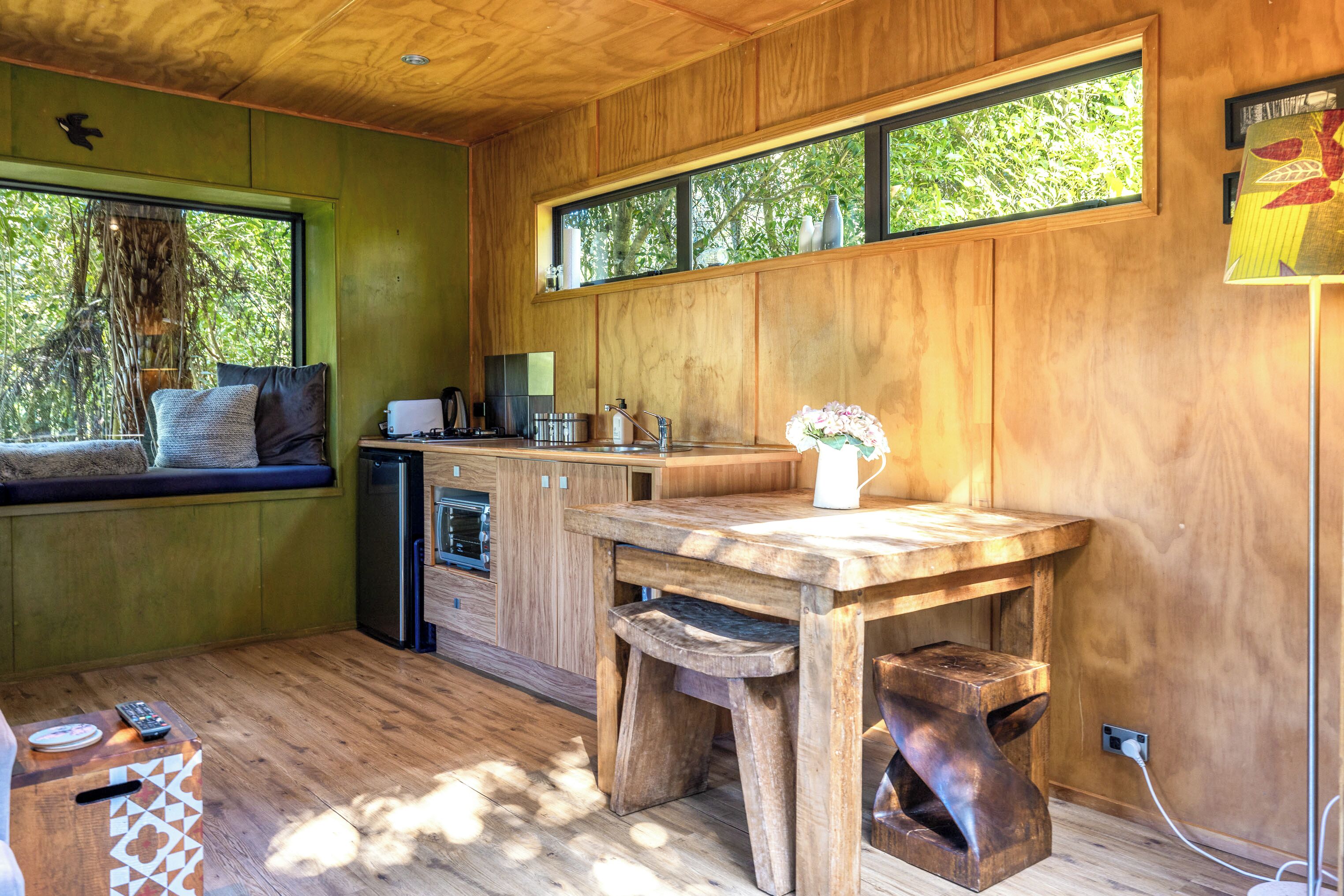 A modern kitchen with wooden cabinetry, a built-in oven, and a window seat with cushions.