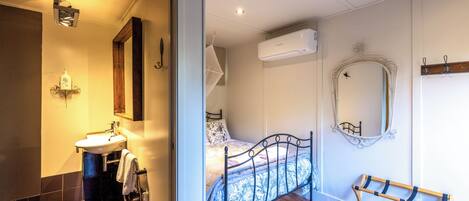 Une chambre à coucher comprenant un lit, une table de chevet, un miroir, un appareil de climatisation et une fenêtre.