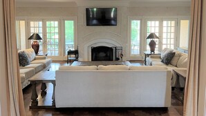 A spacious living room with a fireplace, a large flat-screen TV mounted above it, and two sofas facing the fireplace. - Stunning House with Private Pool and Hot Tub on Rural Estate (Castleton)