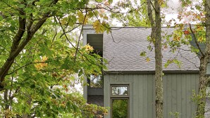 Un bâtiment à deux étages, à l’extérieur gris, avec une porte d’entrée et un petit escalier menant à l’entrée.