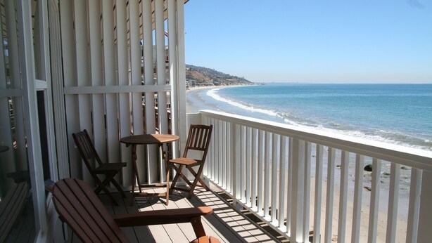 Una terraza de madera con vistas a la playa y el océano.