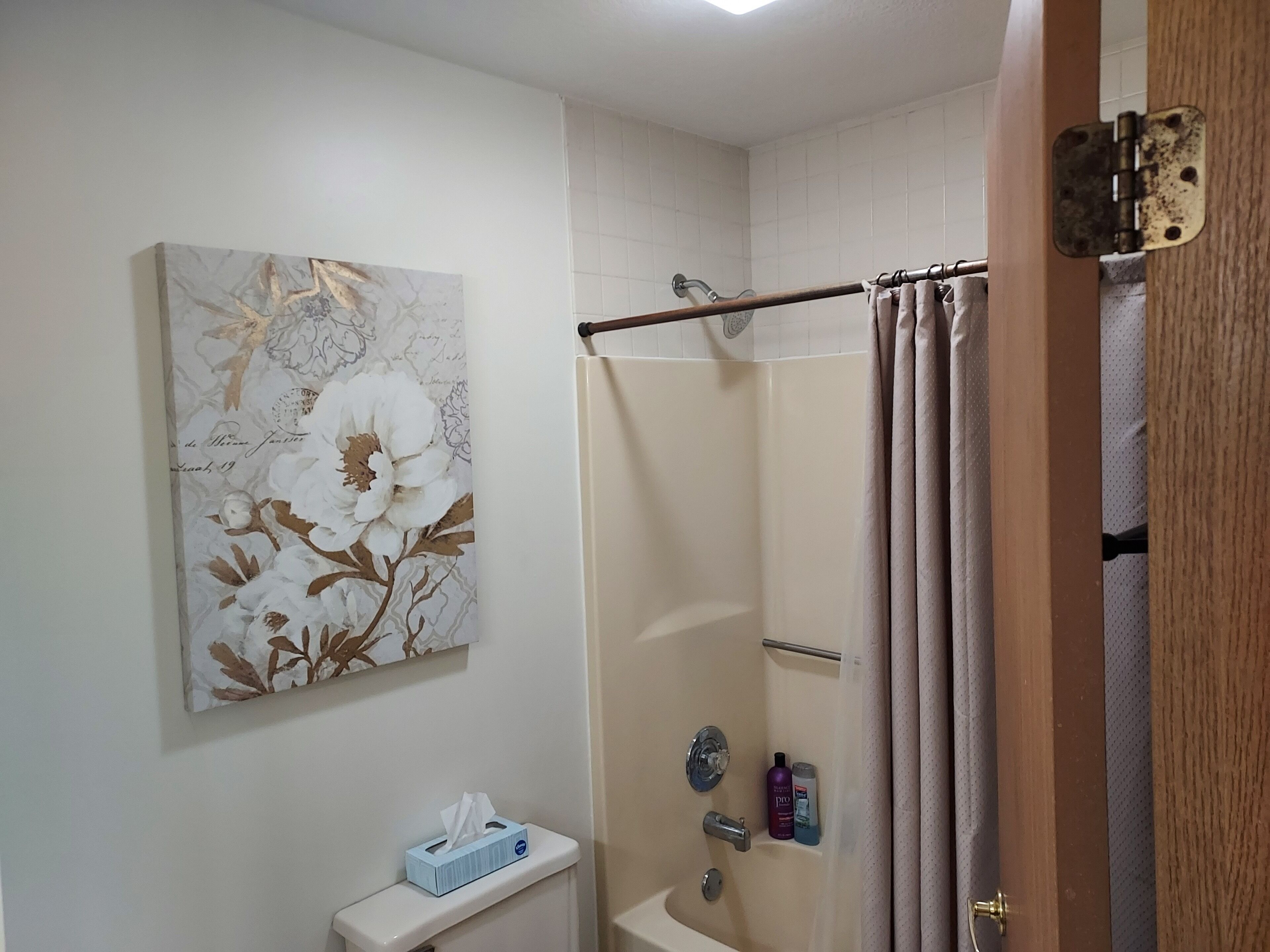 A bathroom with a shower, toilet, and a towel rack.