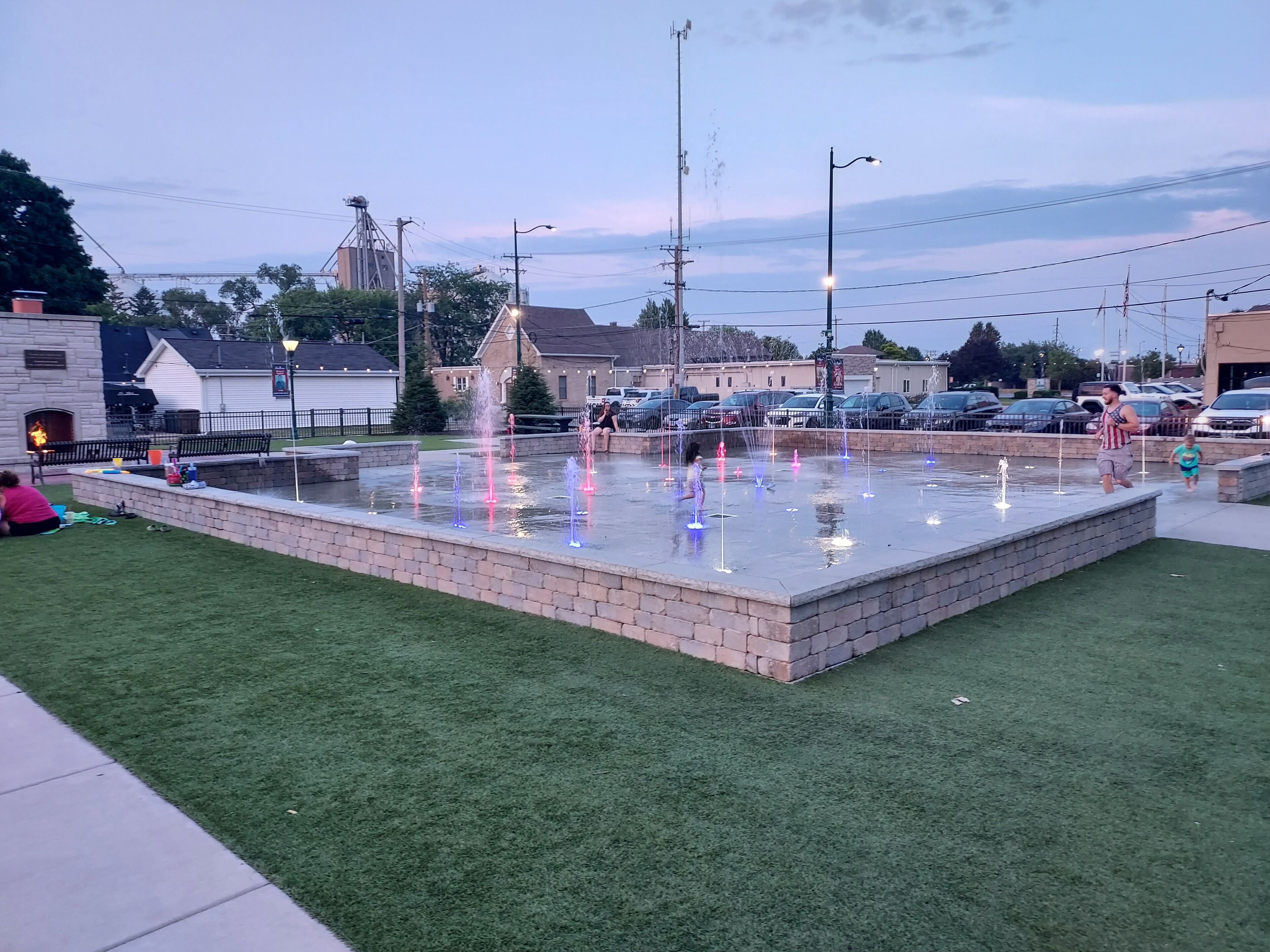 Een openbaar plein met een waterfontein, banken en een vuurplaats.
