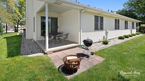Une maison de plain-pied dotée d’un patio couvert, d’un barbecue et d’un foyer extérieur.