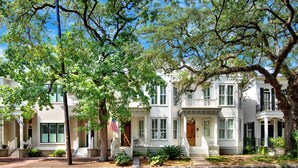 A row of white colonial-style houses with green shutters, a flag, and a well-maintained lawn. - Heated Pool Access | 5*Clean | Flex Cancelation (Savannah)